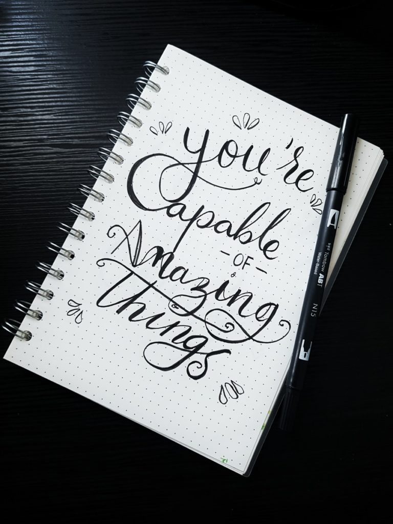 white notebook with black lettering saying you're capable of great things