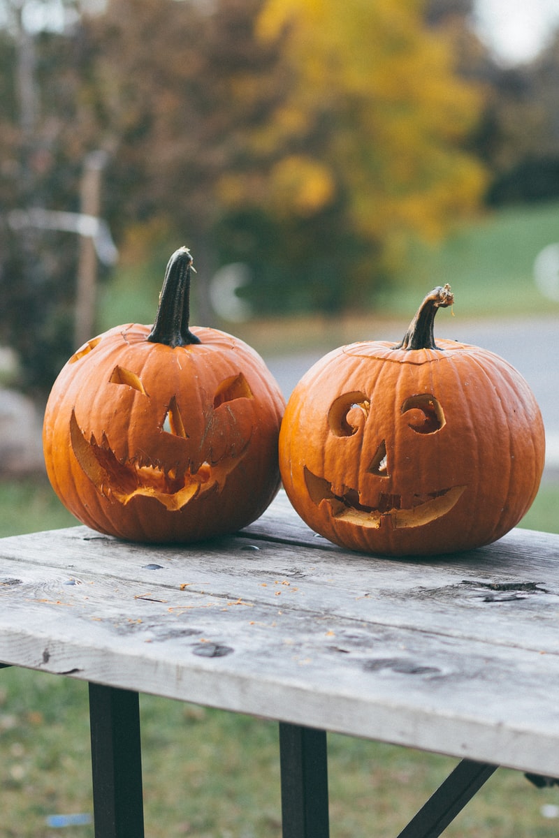 two carved pumpkins on brown wooden table