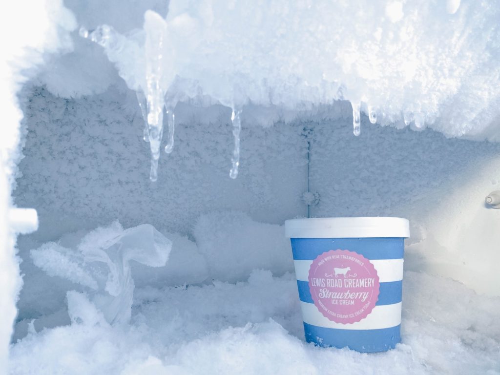 strawberry ice cream container inside a freezer covered in ice