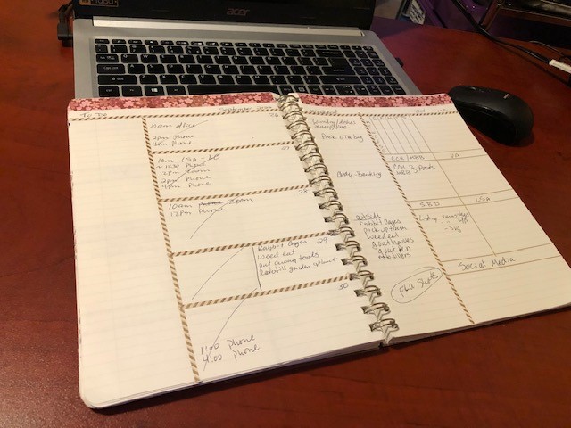 Planner with weekly spread open leaning on laptop keyboard